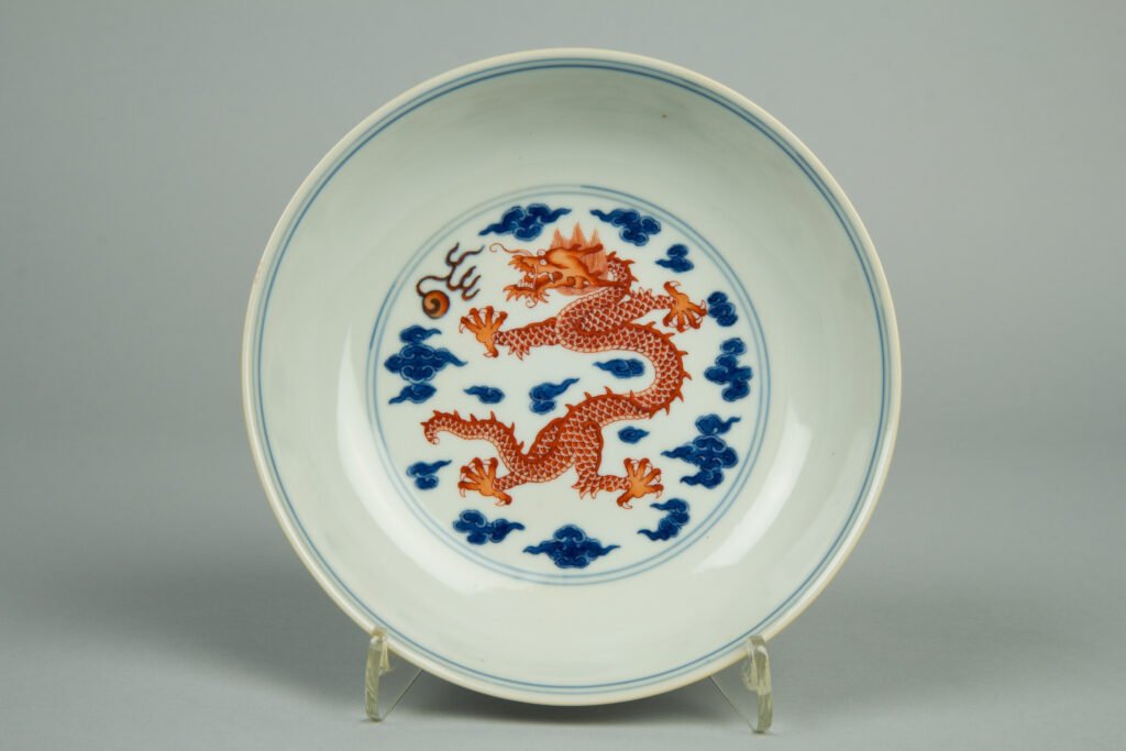 Small porcelain dish with an iron-red dragon and flaming pearl inside underglaze blue rings, Qing dynasty. The Metropolitan Museum of Art, 1993.386.2.