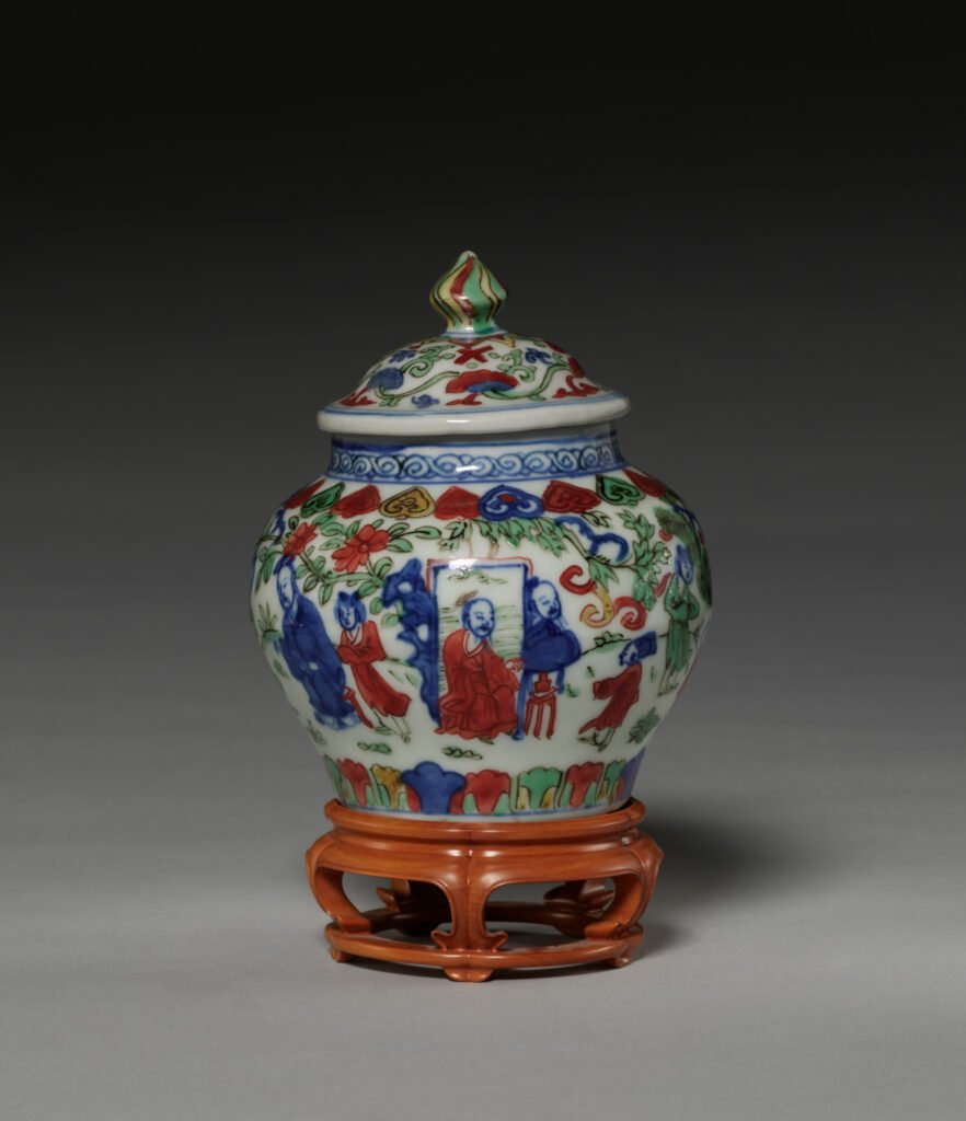 Small Ming wucai covered jar painted with figures in underglaze blue and overglaze red, green and yellow enamels, Wanli reign, on a stand. Cleveland Museum of Art, 1957.62.